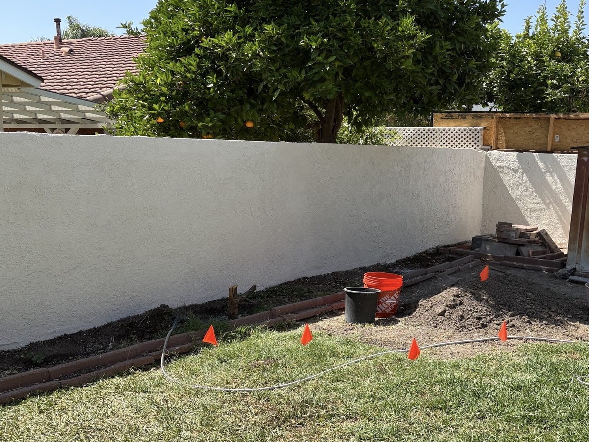 After: wall crack repaired and freshly painted, with new irrigation and brick edging