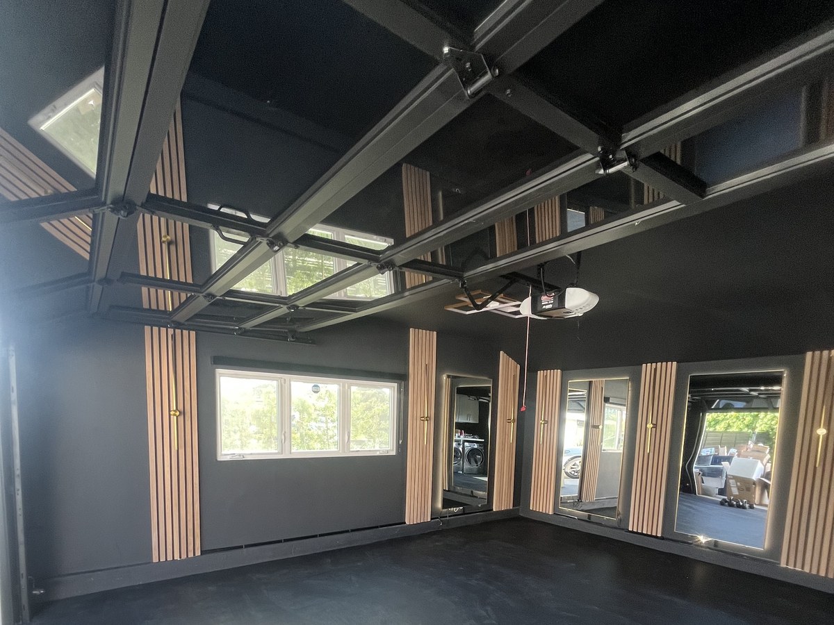 Garage fully converted into a home gym with black walls, wood slat accents and mirrors